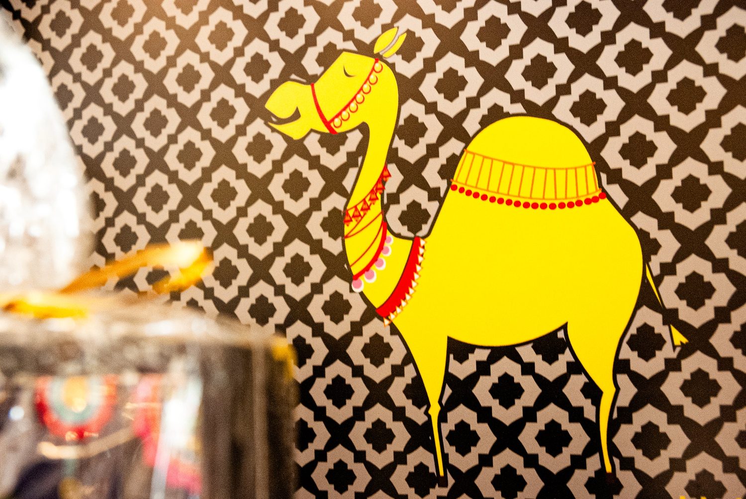 Yellow illustrated camel on patterned black and white wallpaper in a store interior